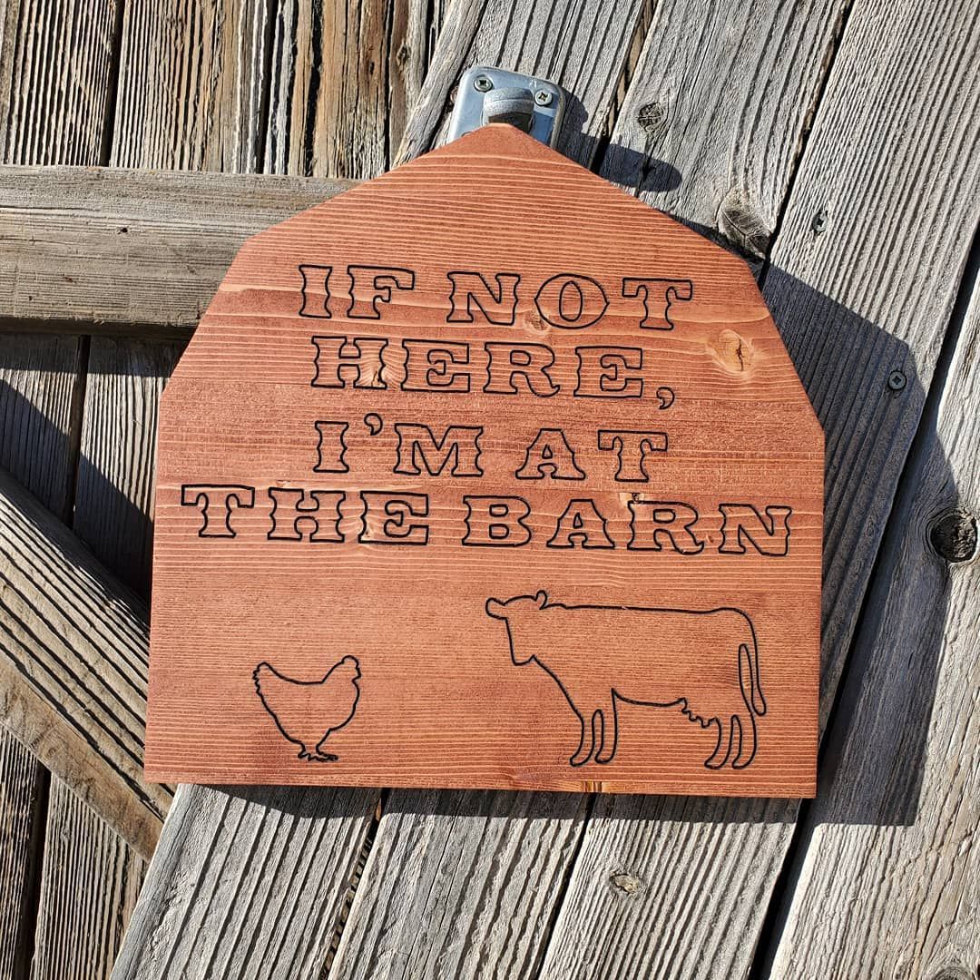Wooden barn-shaped sign with etched text: