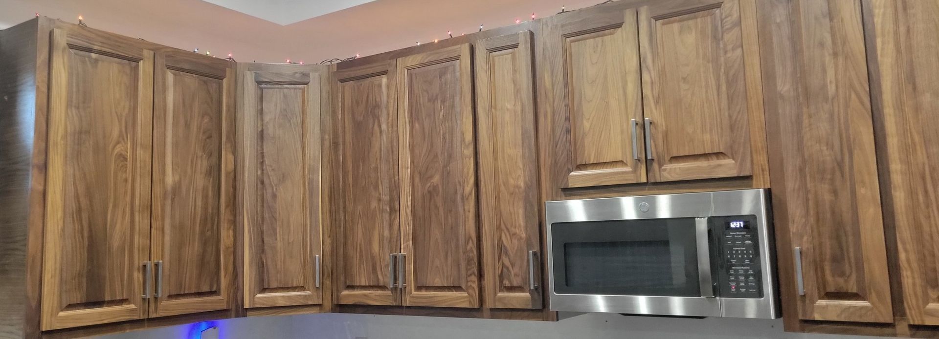 Wooden kitchen cabinets with a stainless steel microwave.