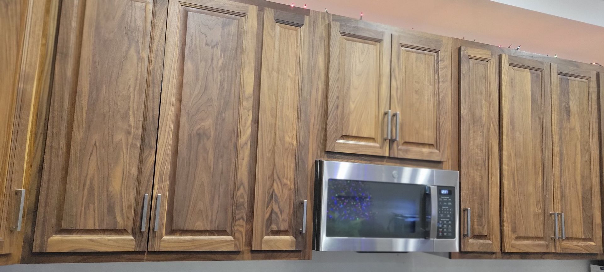 Brown wooden kitchen cabinets with a stainless steel microwave.