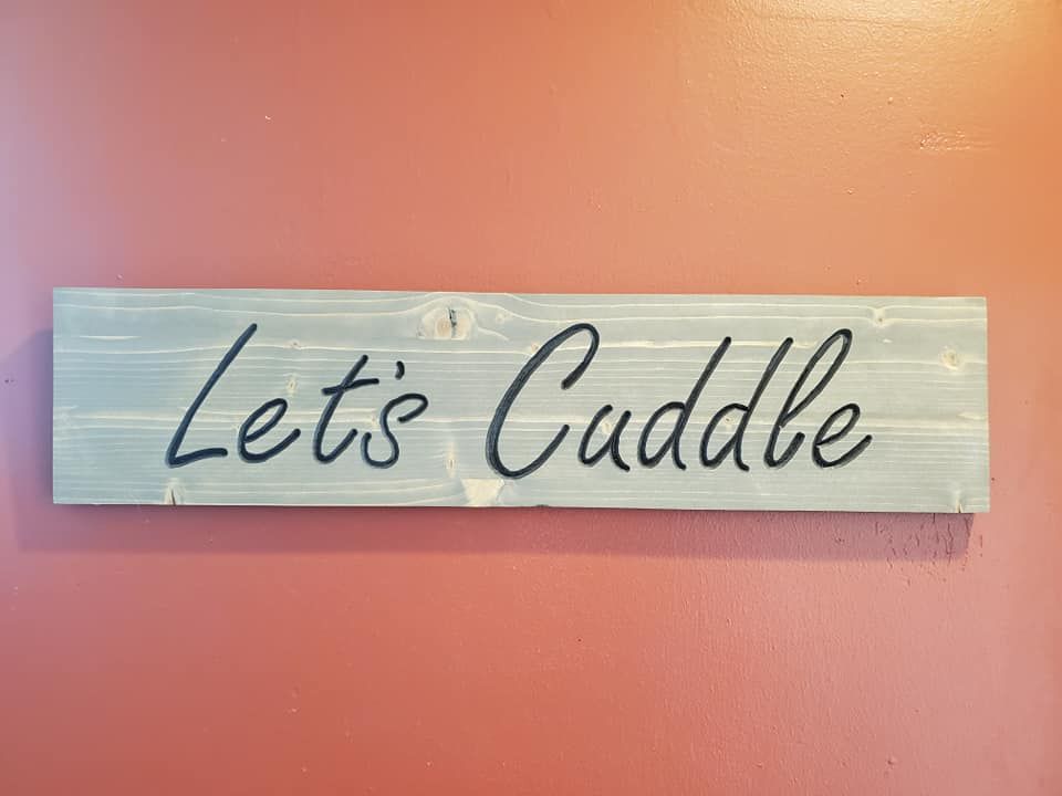 Wooden sign on a red wall that says