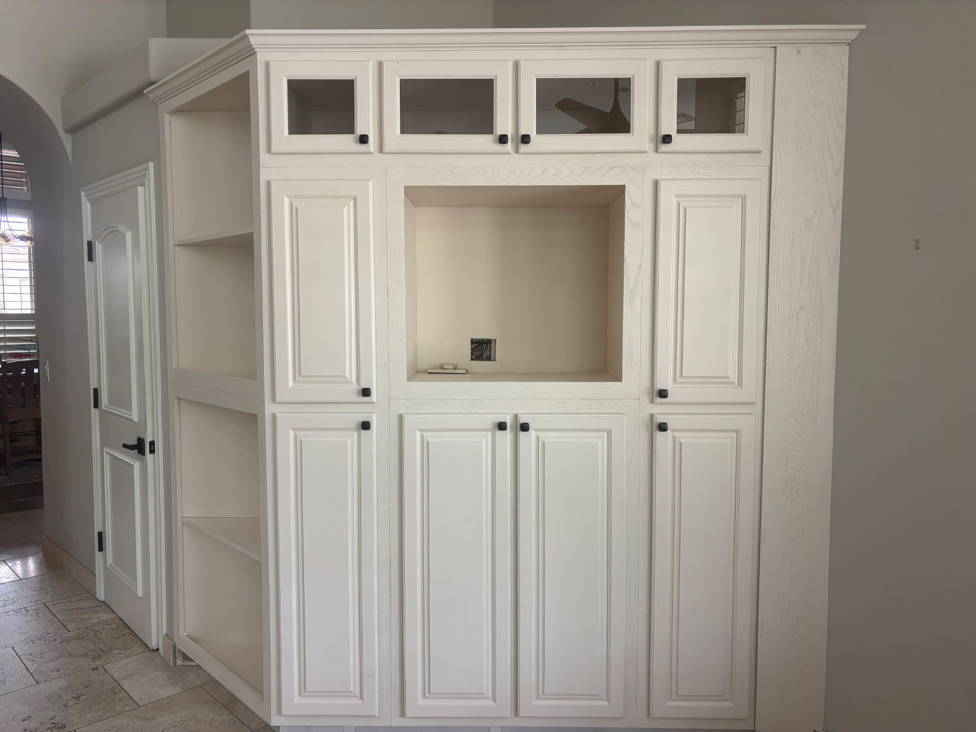 White built-in cabinet with open shelves, solid and glass door storage.