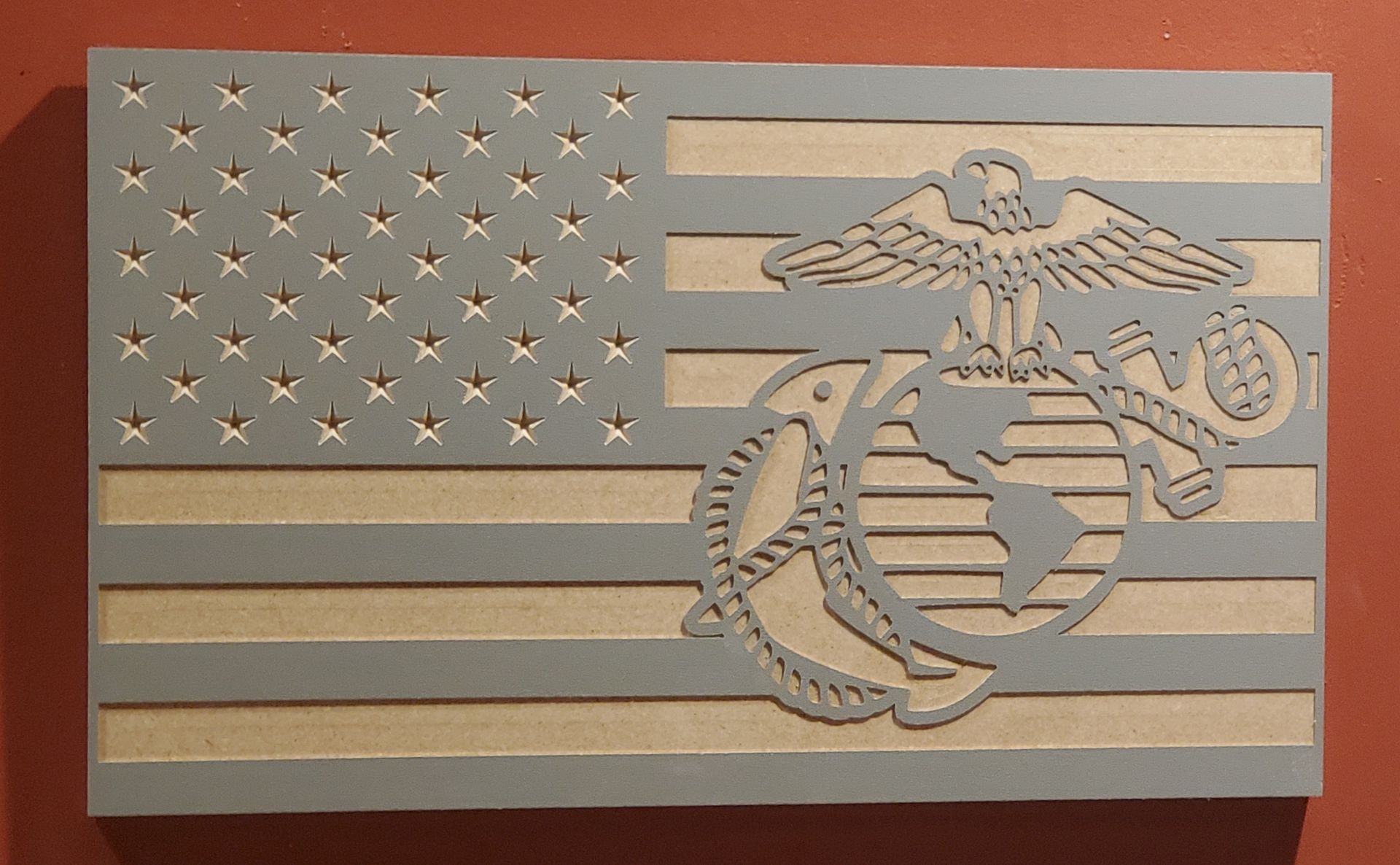 Gray and beige carved wooden flag with Marine Corps emblem.