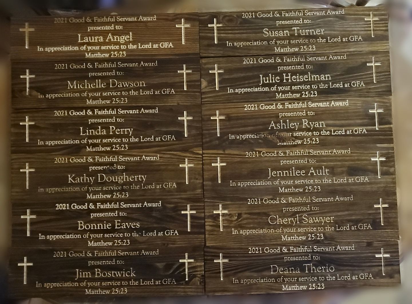 Wooden plaques with names and Bible verses, possibly awards, arranged in a grid.