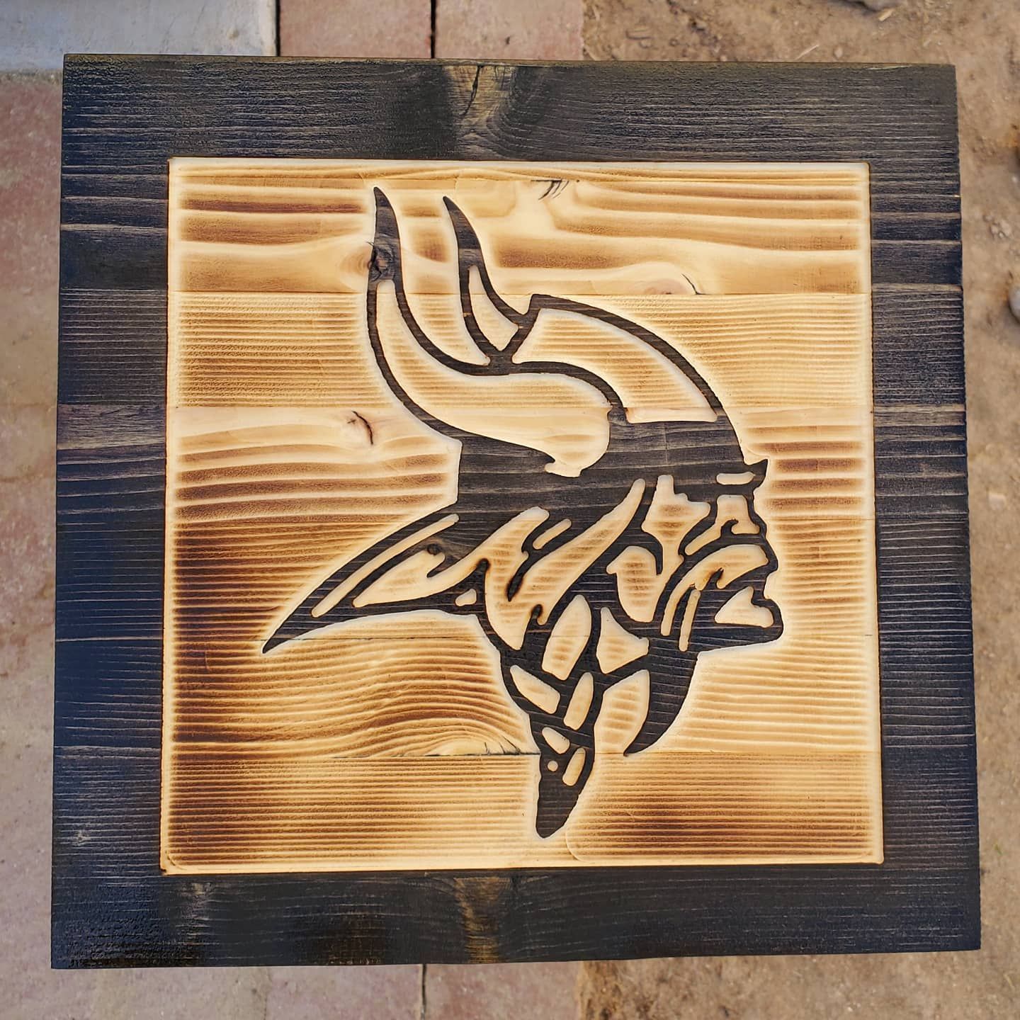 Minnesota Vikings logo burned onto wood. Dark brown frame.