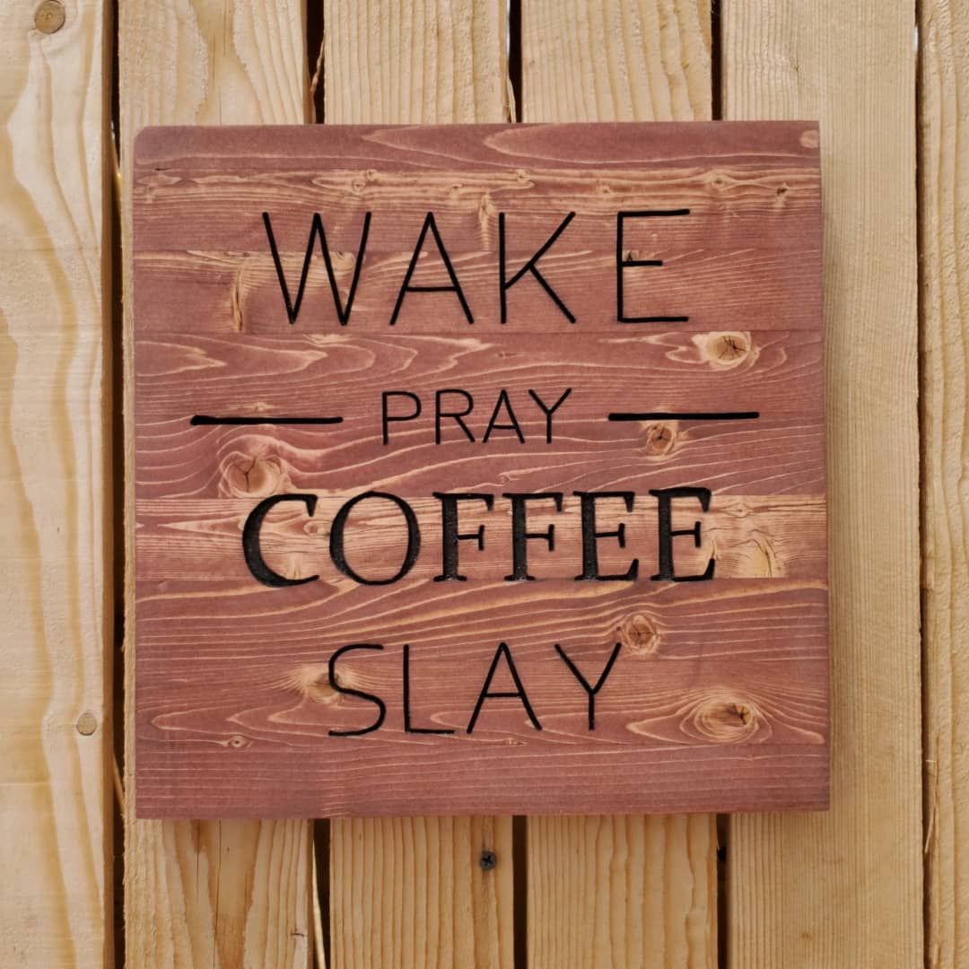Wooden sign with “WAKE, PRAY, COFFEE, SLAY” in black letters against a reddish-brown background.