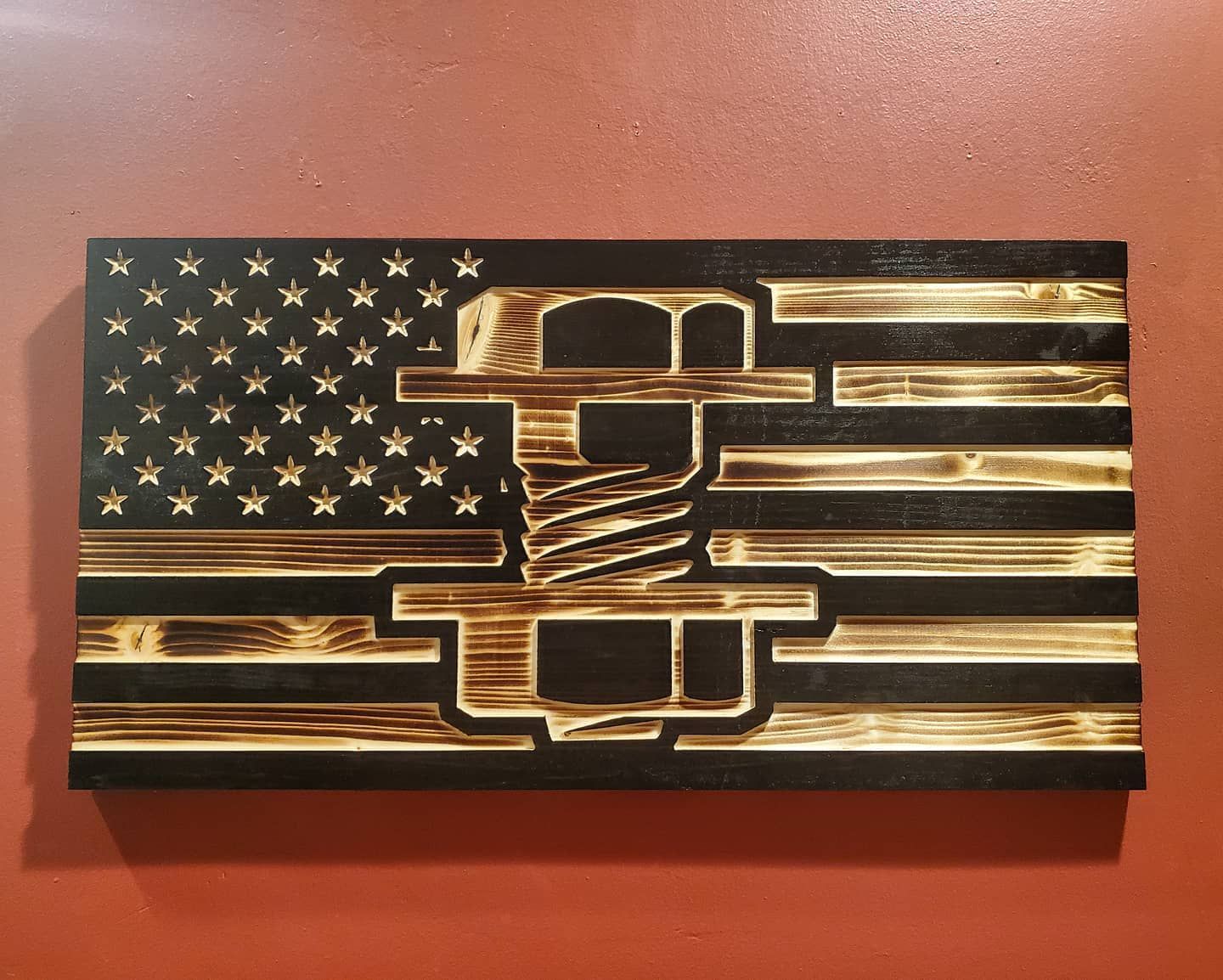 Wooden American flag with a cut-out vise in the center, set against a reddish-brown wall.