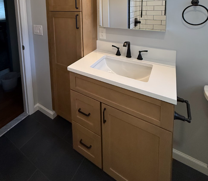 Modern bathroom vanity with white sink, black faucet, and wood cabinets against light gray walls