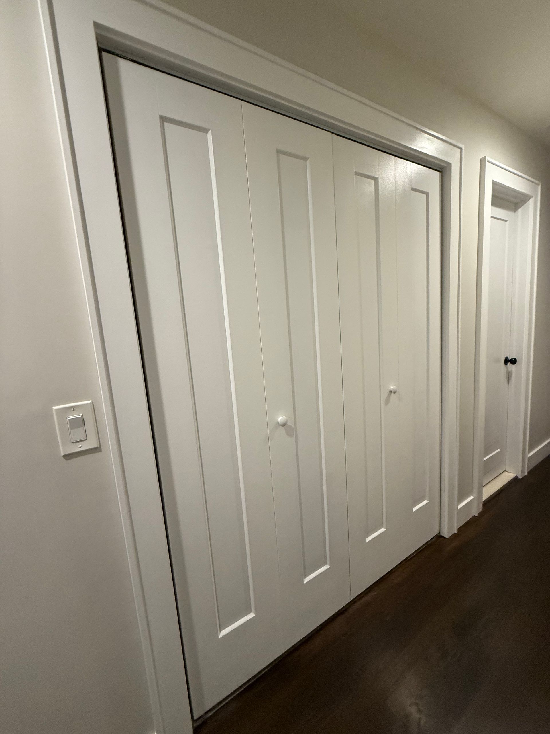 Hallway with white closet doors and a dark wood floor