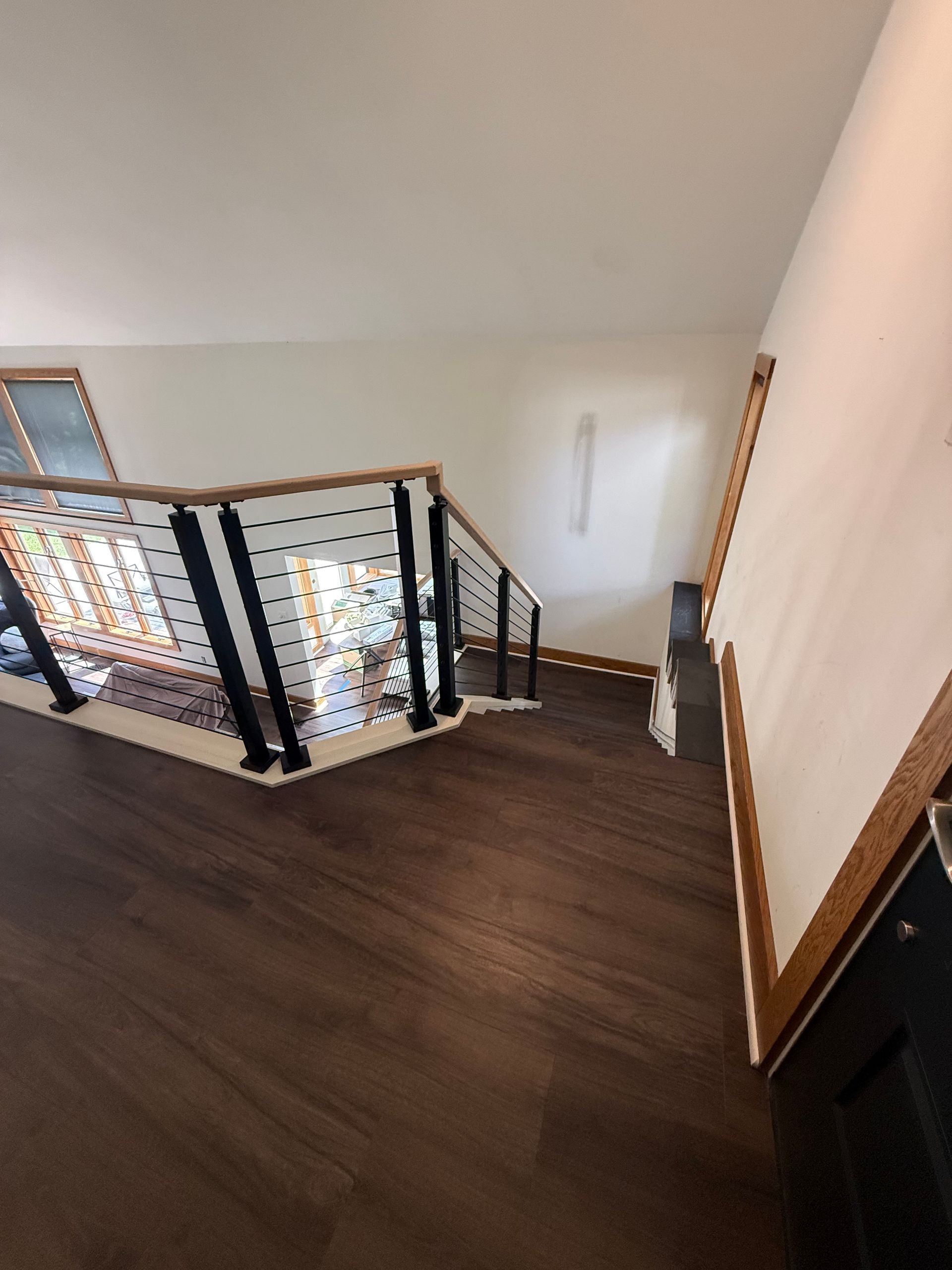Stairwell landing with dark wood floor, black railing, and white walls in a modern interior.