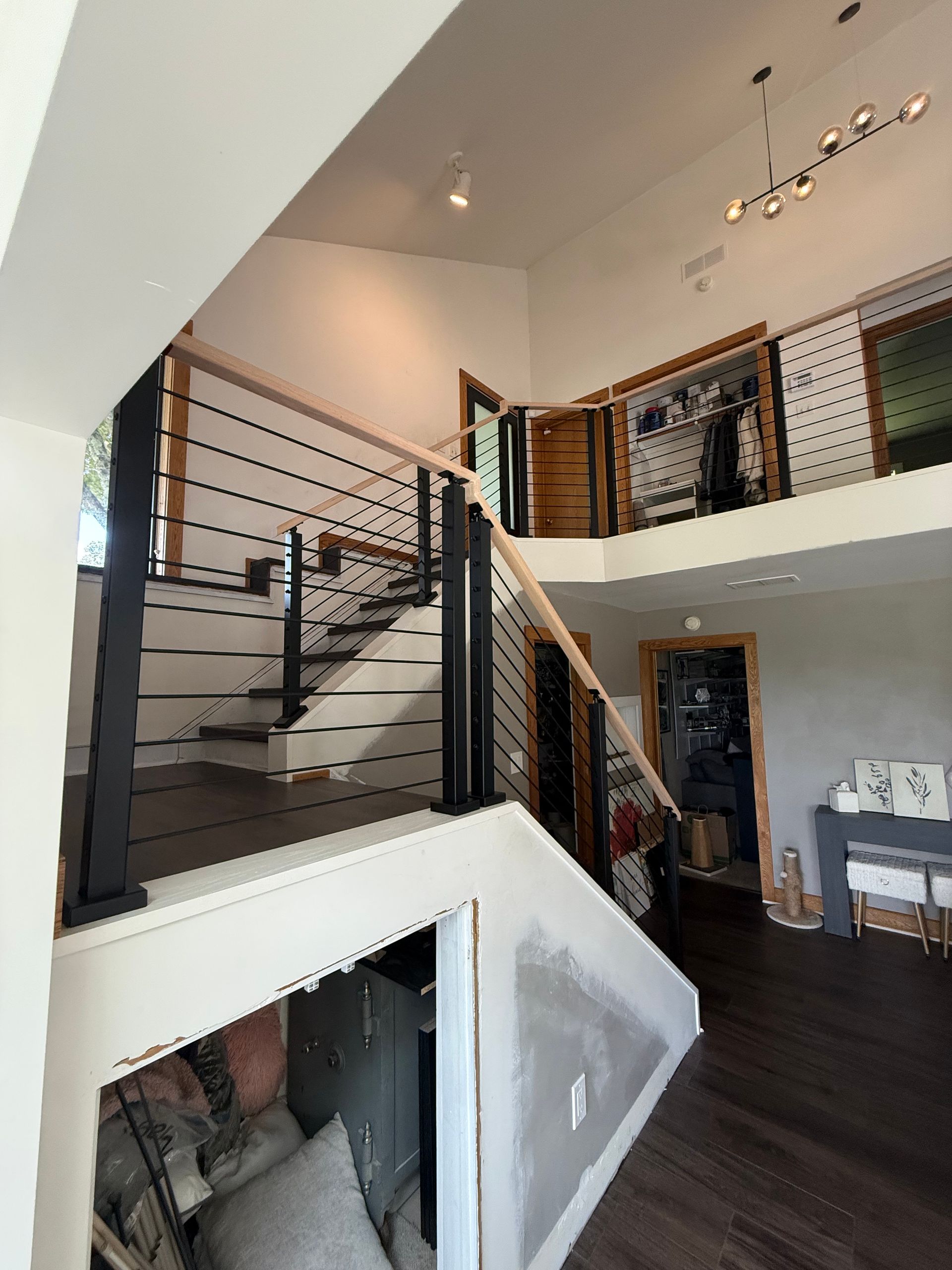 Modern loft interior with open staircase, loft railing, dark wood floors, and high ceilings