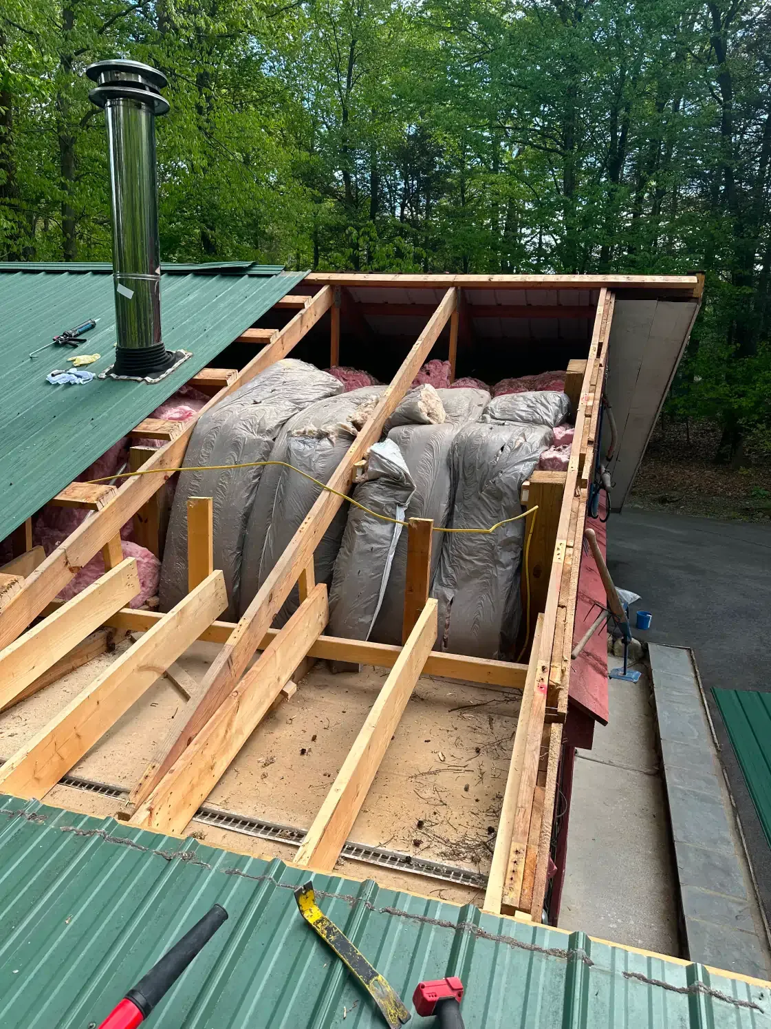 Roof partially open, revealing wooden framing and insulation. Green metal roof with chimney.