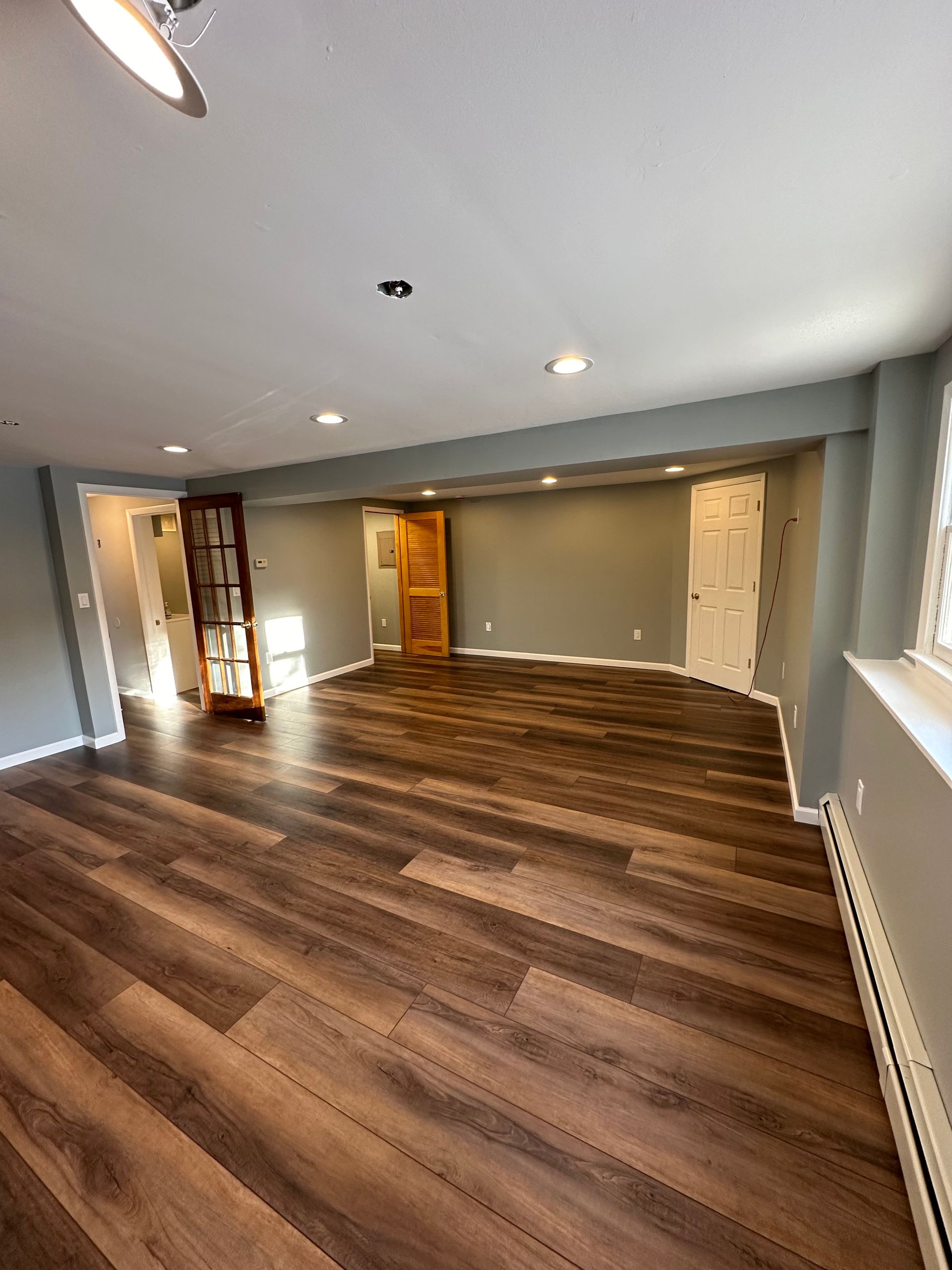 Empty modern room with dark wood floors, recessed lights, and gray walls