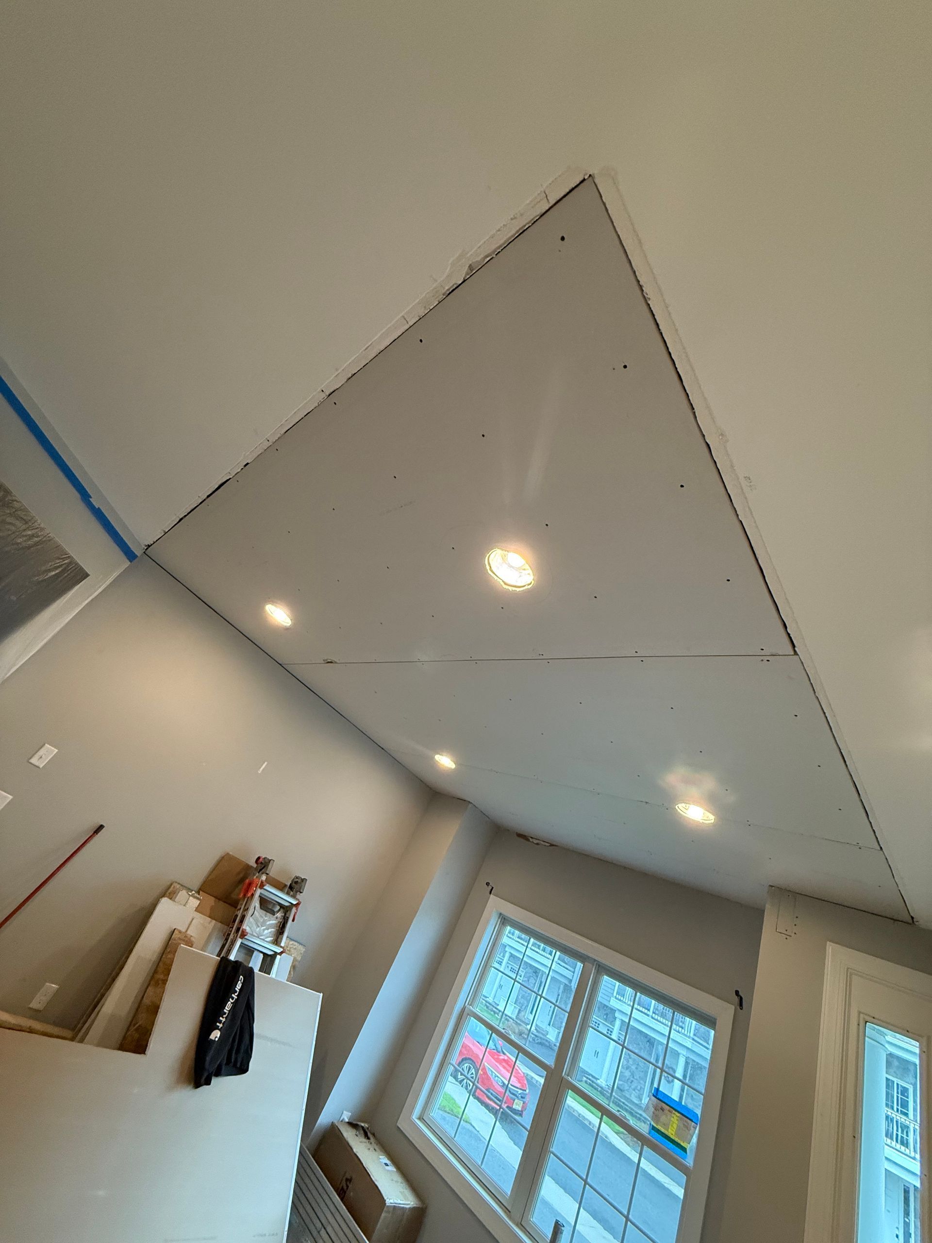 Interior room with slanted white ceiling, recessed lights, and a window on the wall.