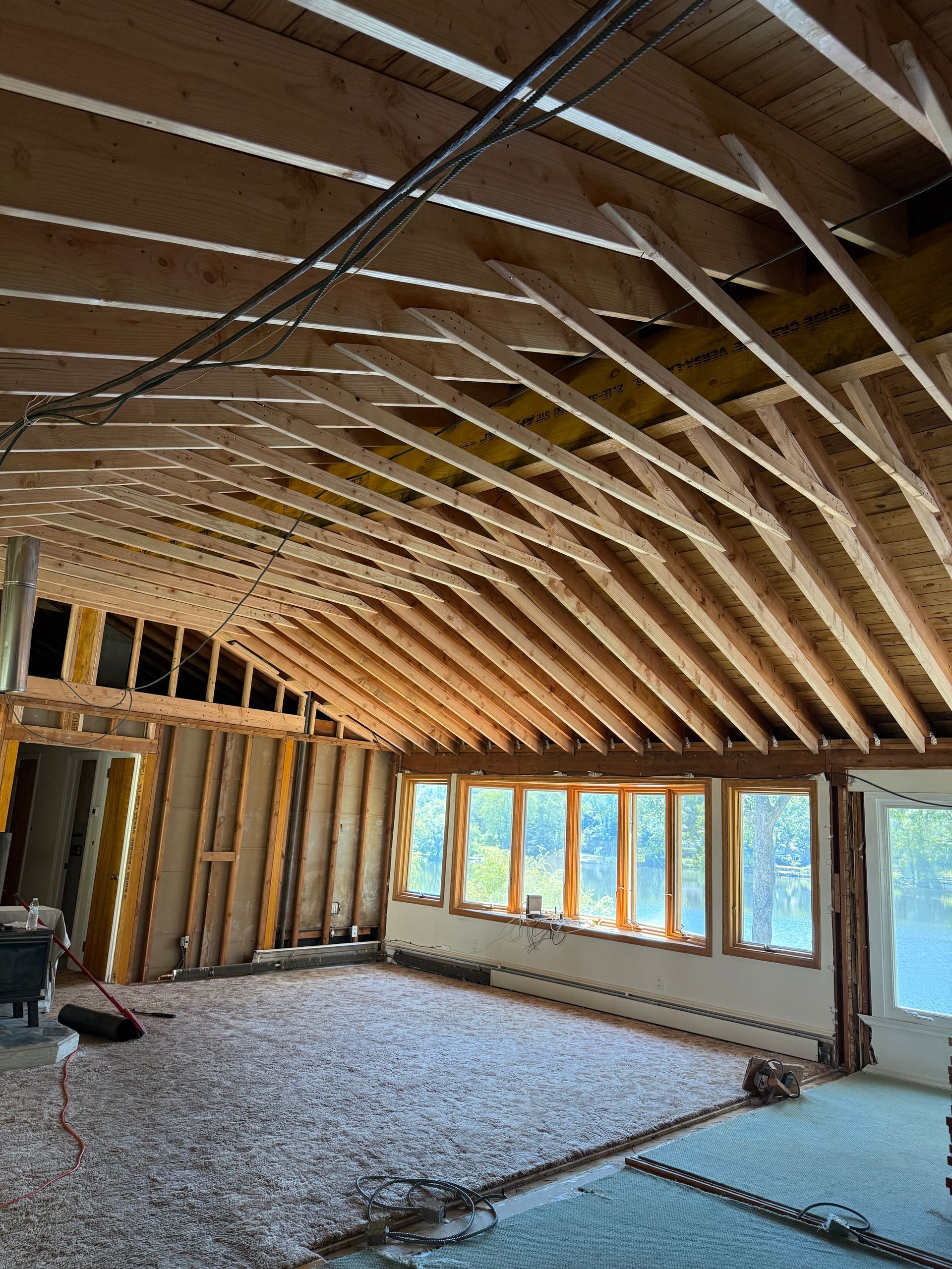 Interior view of a room under construction with exposed wooden beams and insulation in the ceiling.