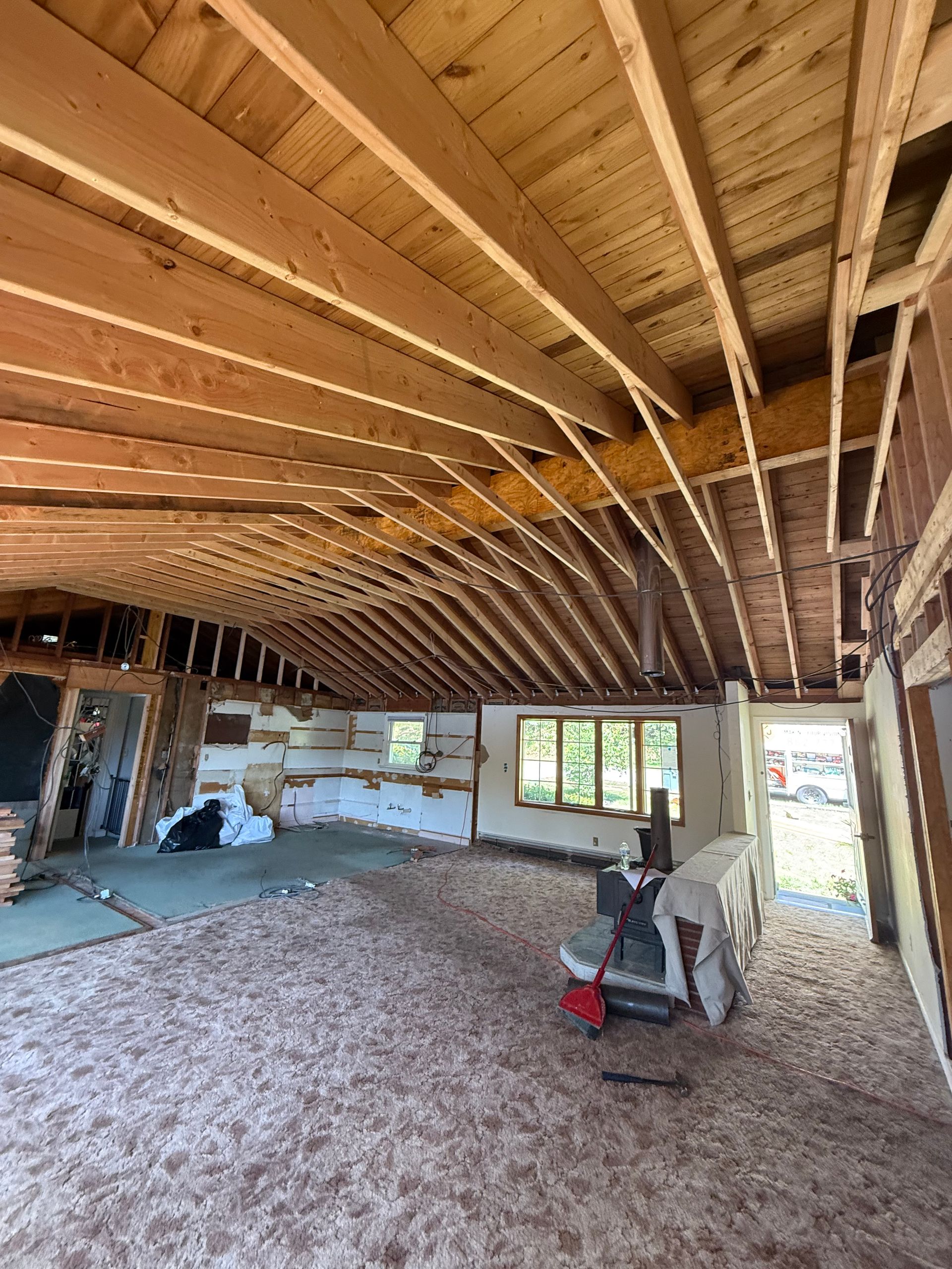 Interior of a house under renovation. Exposed wooden beams and studs. Debris on the floor.