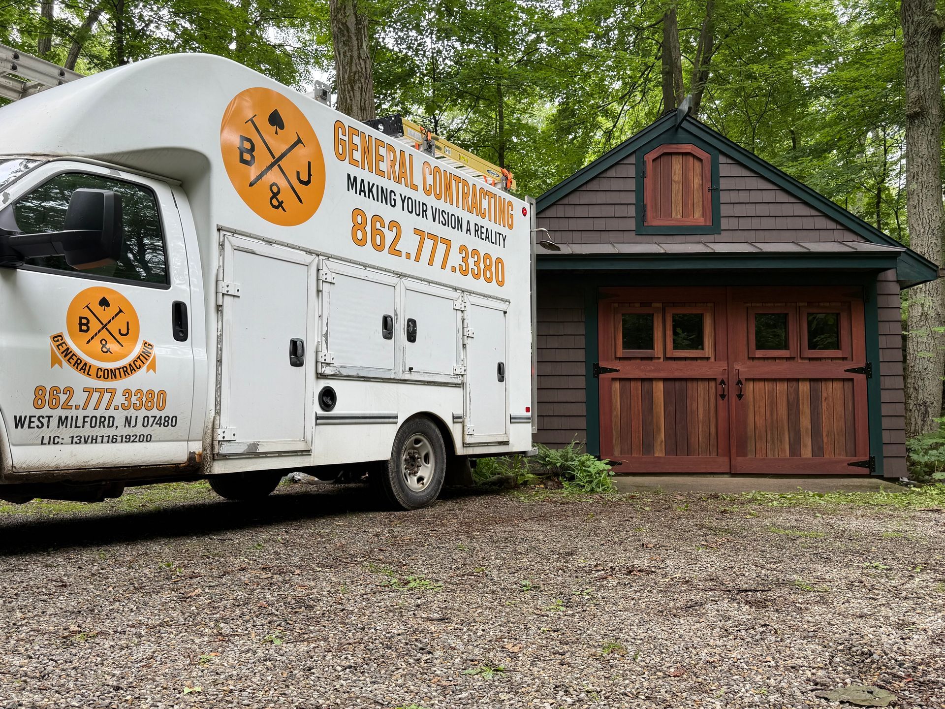 White work truck with logo parked next to a brown wooden garage.