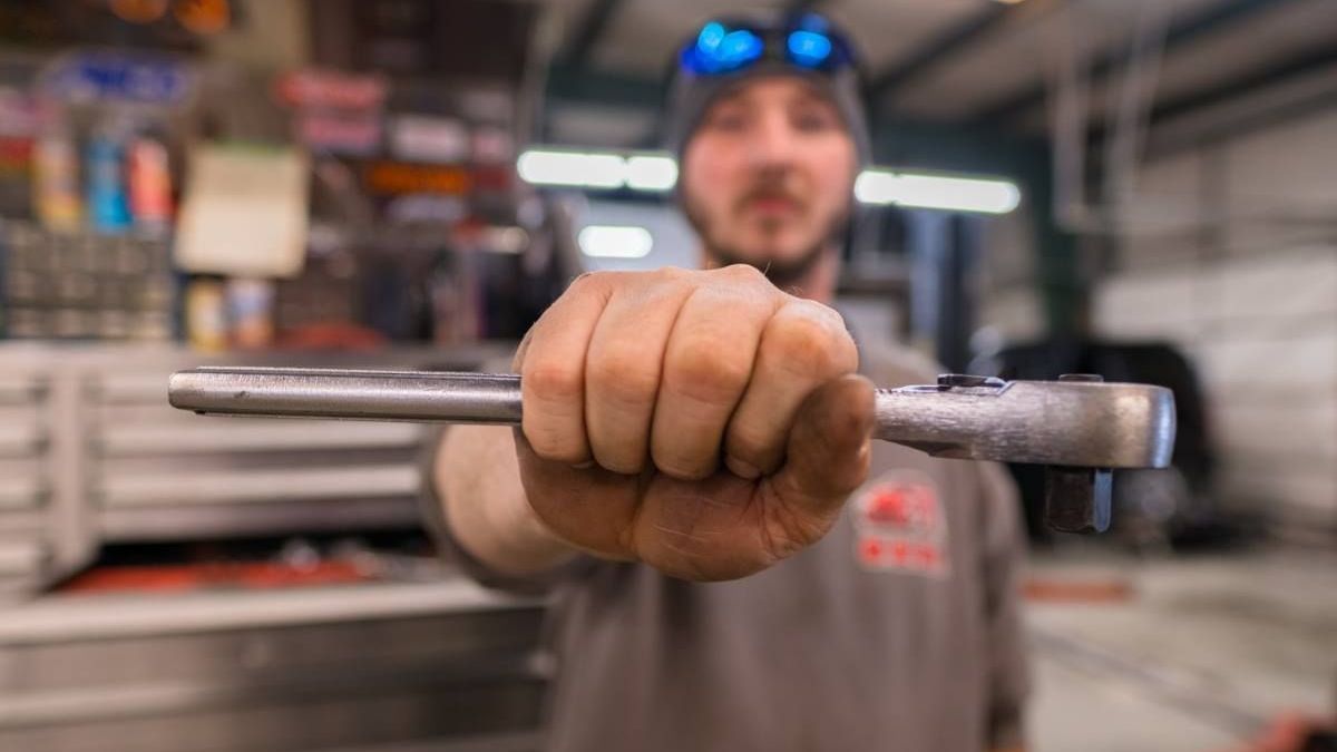 a man is holding a wrench in his right hand