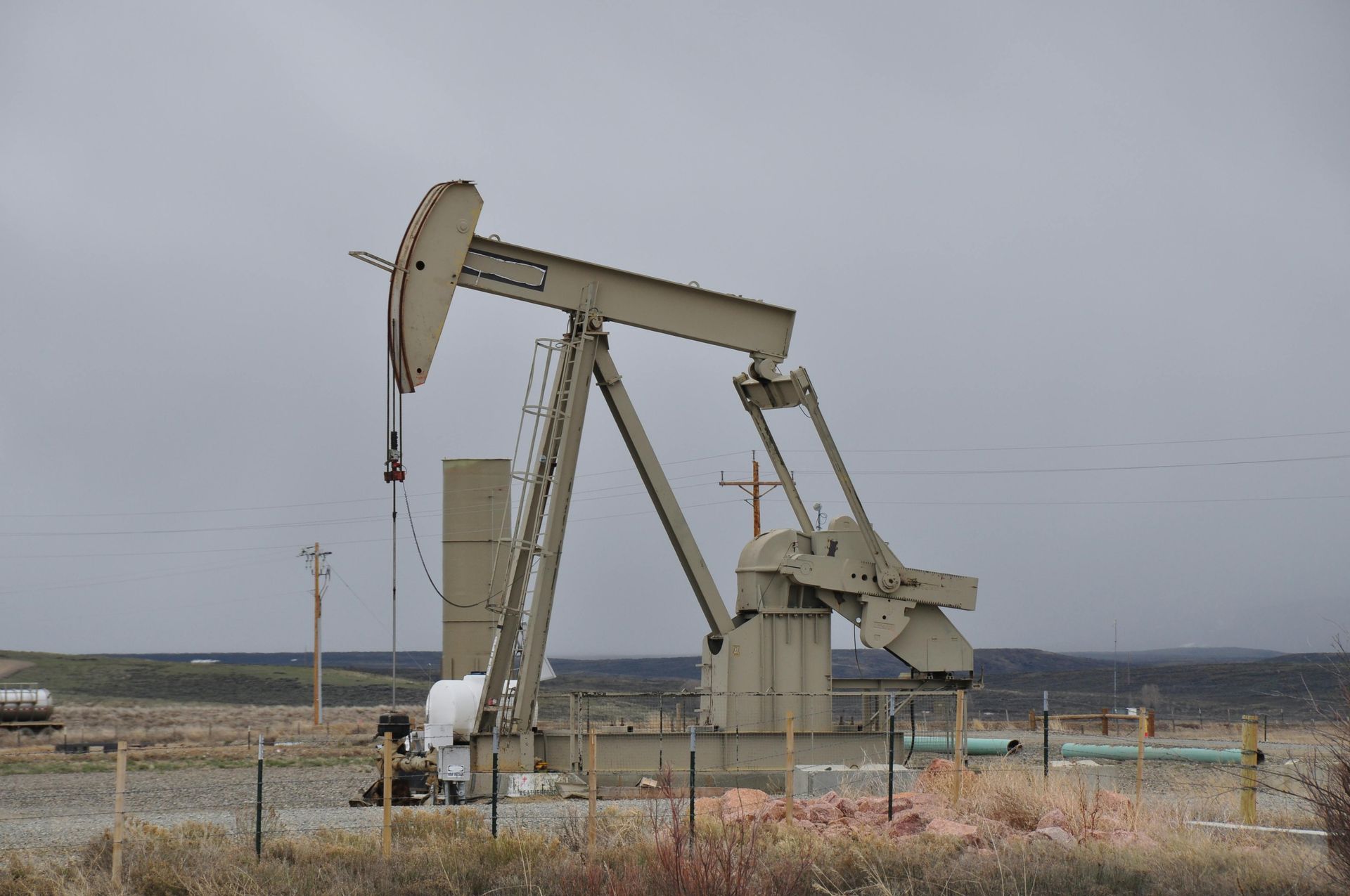 Oil pump jack in a field under a cloudy sky.