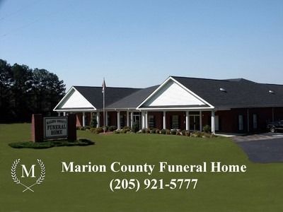 Marion County Funeral Home sign in front of a brick building and lawn under a blue sky