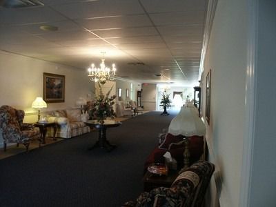Elegant hotel corridor with chandeliers, sofas, and wall art along a carpeted hallway