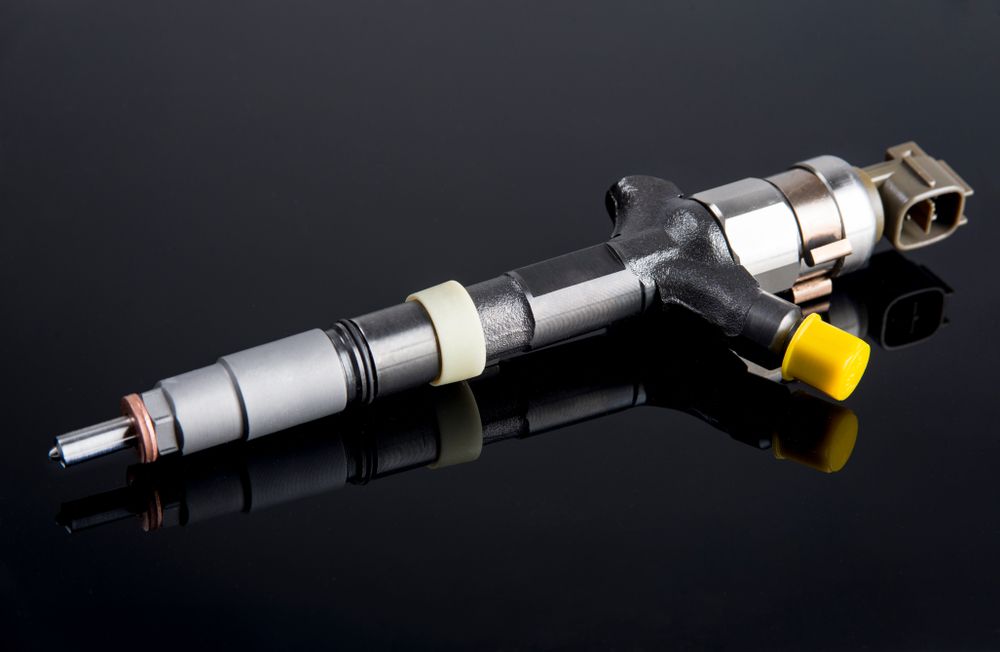 A Close Up Of A Fuel Injector On A Black Surface — Hastings Diesel Service In Wauchope, NSW