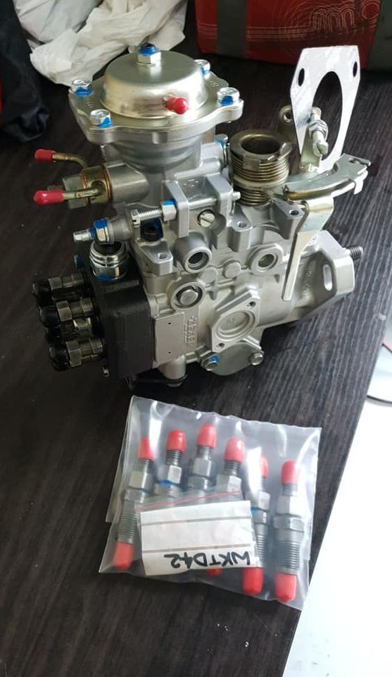 A Fuel Pump Is Sitting On A Wooden Table Next To A Bag Of Injectors — Hastings Diesel Service In Wauchope, NSW
