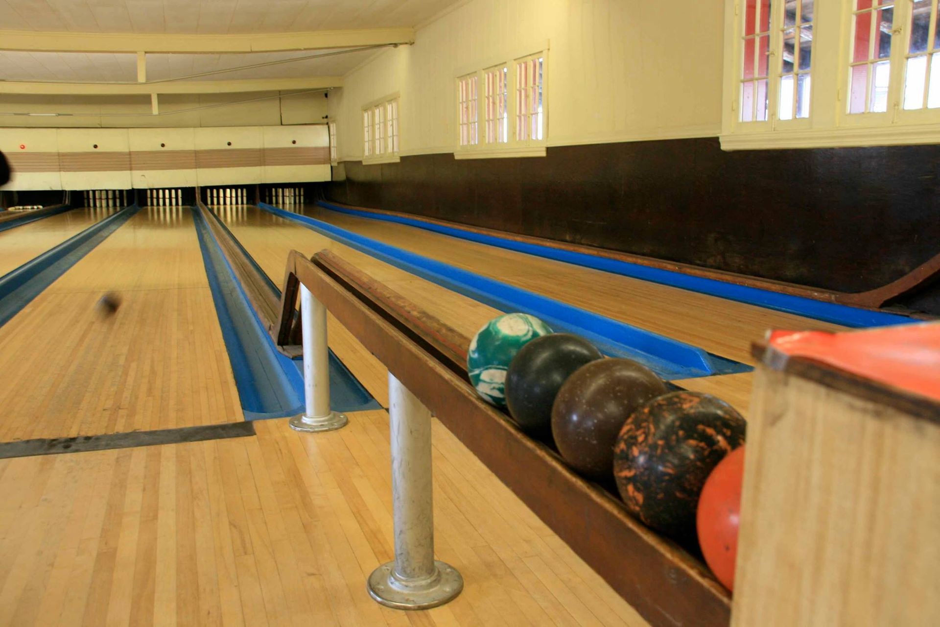 A bowling alley with bowling balls in a row