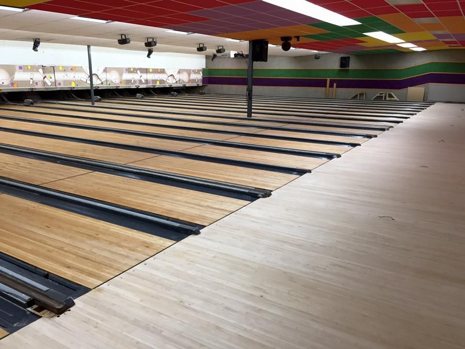 An empty bowling alley with wooden lanes and a colorful ceiling