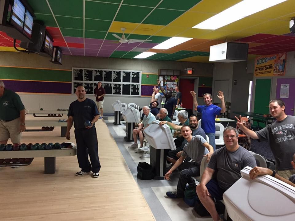 A group of men are playing bowling in a bowling alley