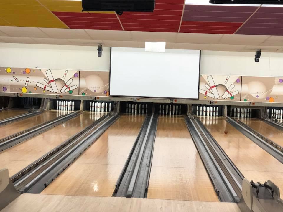 A bowling alley with a large screen on the ceiling
