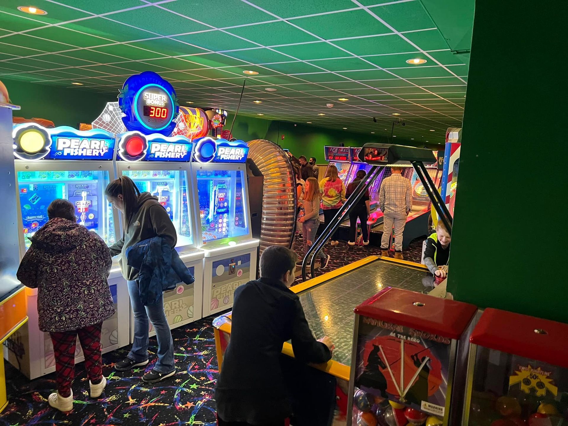 A group of people are playing arcade games in an amusement park.
