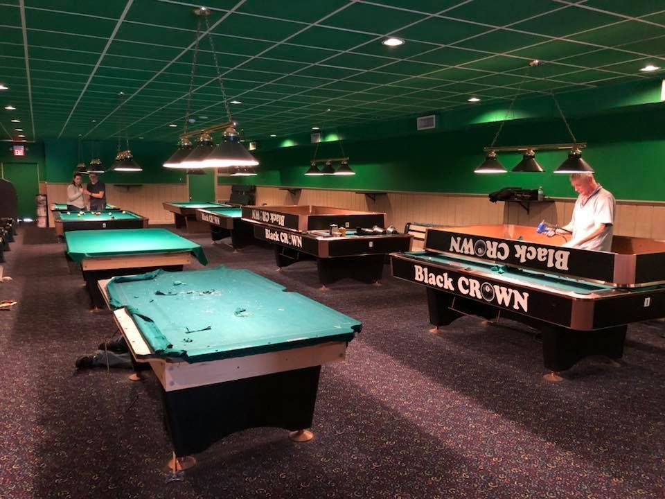 A pool hall with many pool tables and a sign that says black crown