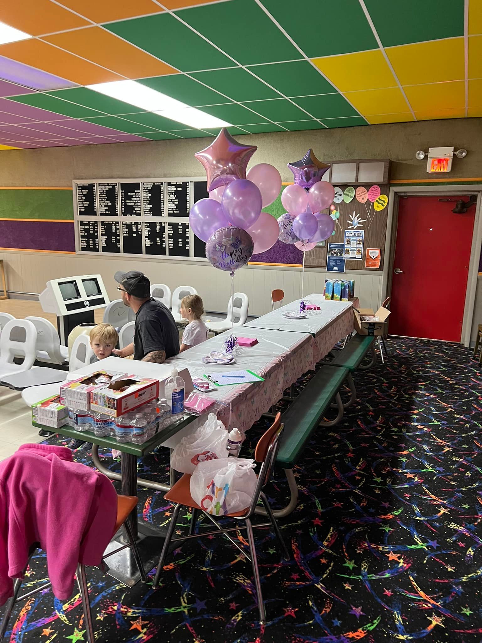 A group of people are sitting at tables in a room with balloons on the ceiling.