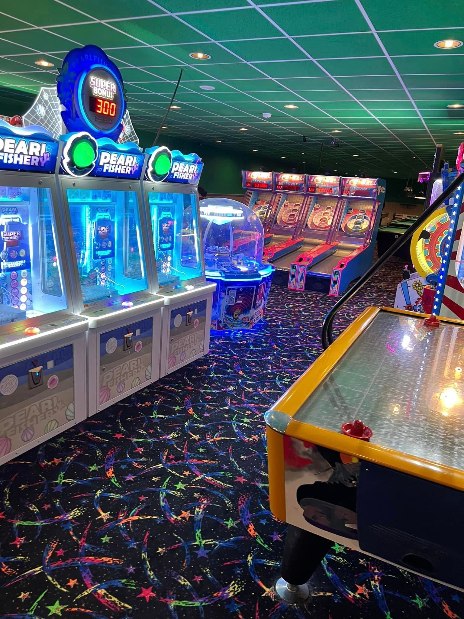 A bunch of arcade games are lined up in a room.