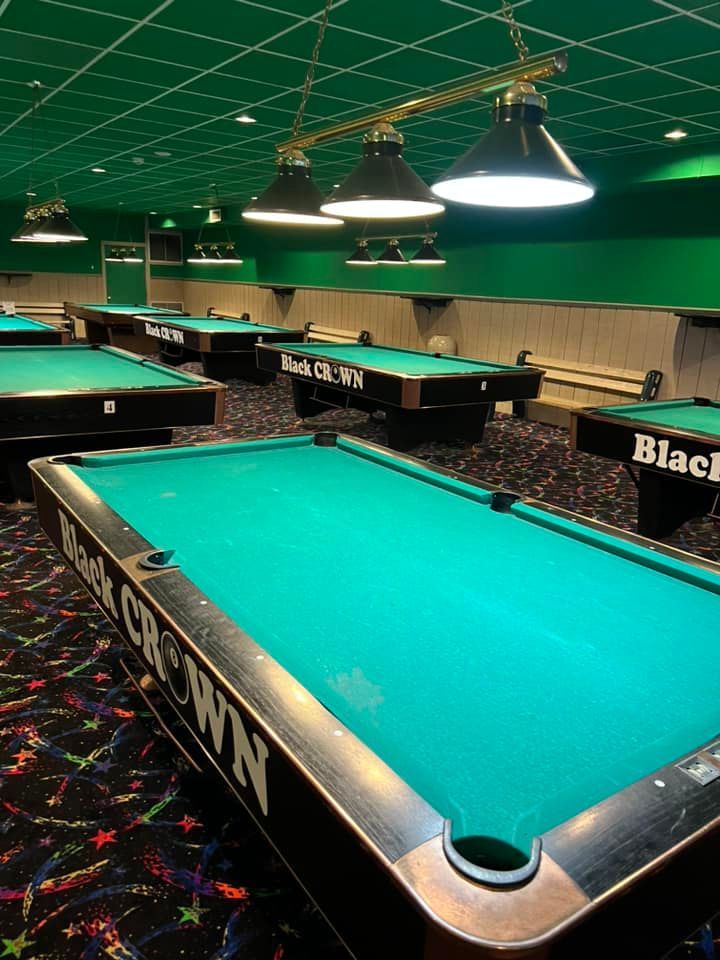 A pool hall with pool tables that say black crown