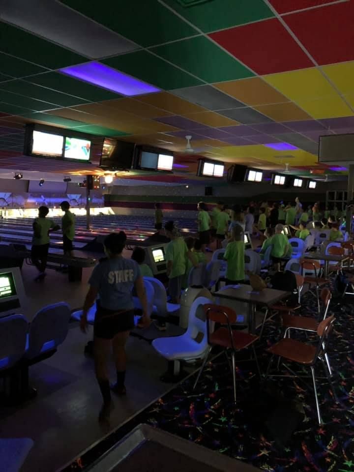A group of people are playing bowling in a dark bowling alley.