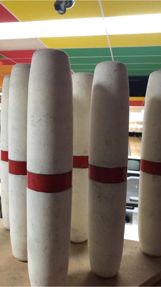 A row of bowling pins with red stripes on them