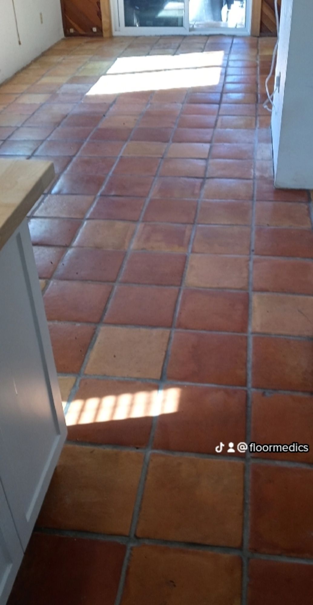 A kitchen with a tiled floor and a sliding glass door.