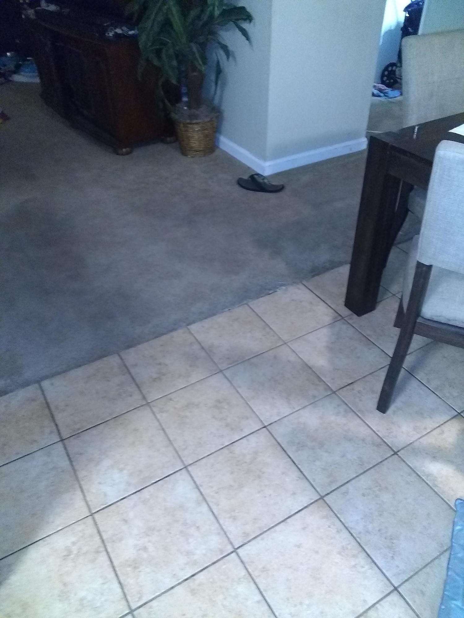 A tiled floor in a living room with a table and chairs
