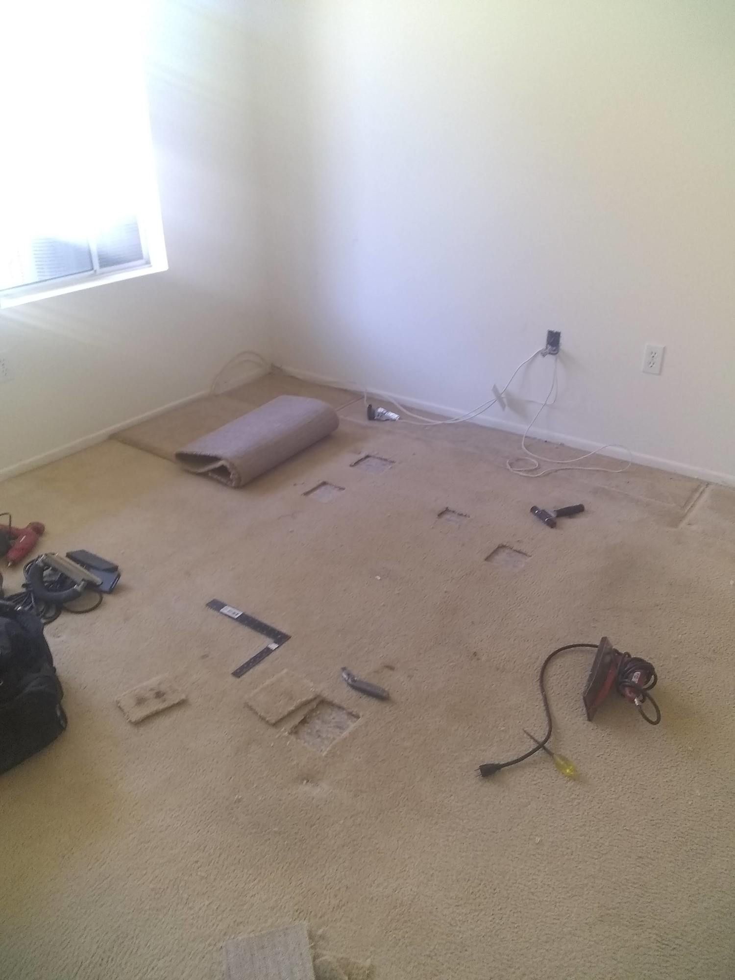 A room with a carpet on the floor and tools on the floor.