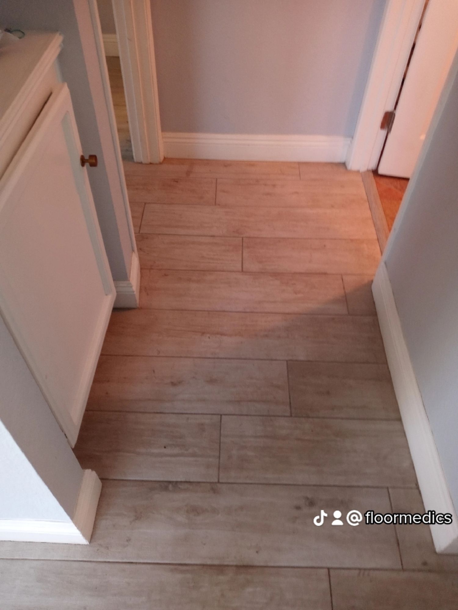 A hallway with a wooden floor and white cabinets