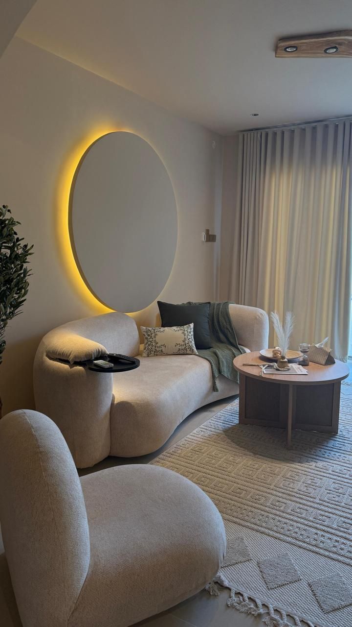 Cozy living room with curved sofa, boucle chair, round coffee table, and large circular wall art.