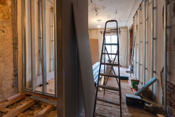A ladder is sitting in the middle of a room under construction.