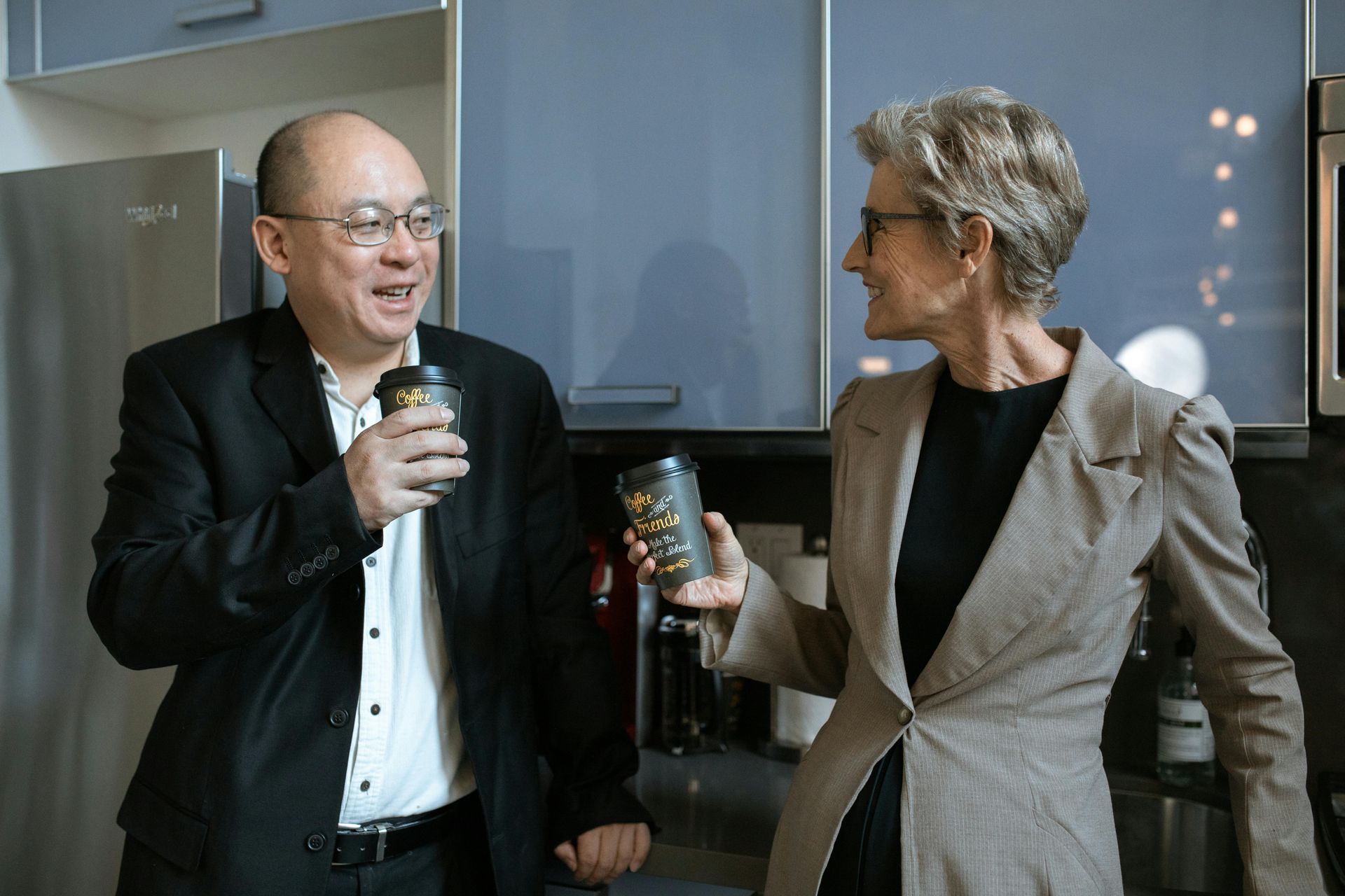 A photo of an adult man and woman holding a coffee cup and talks about business.