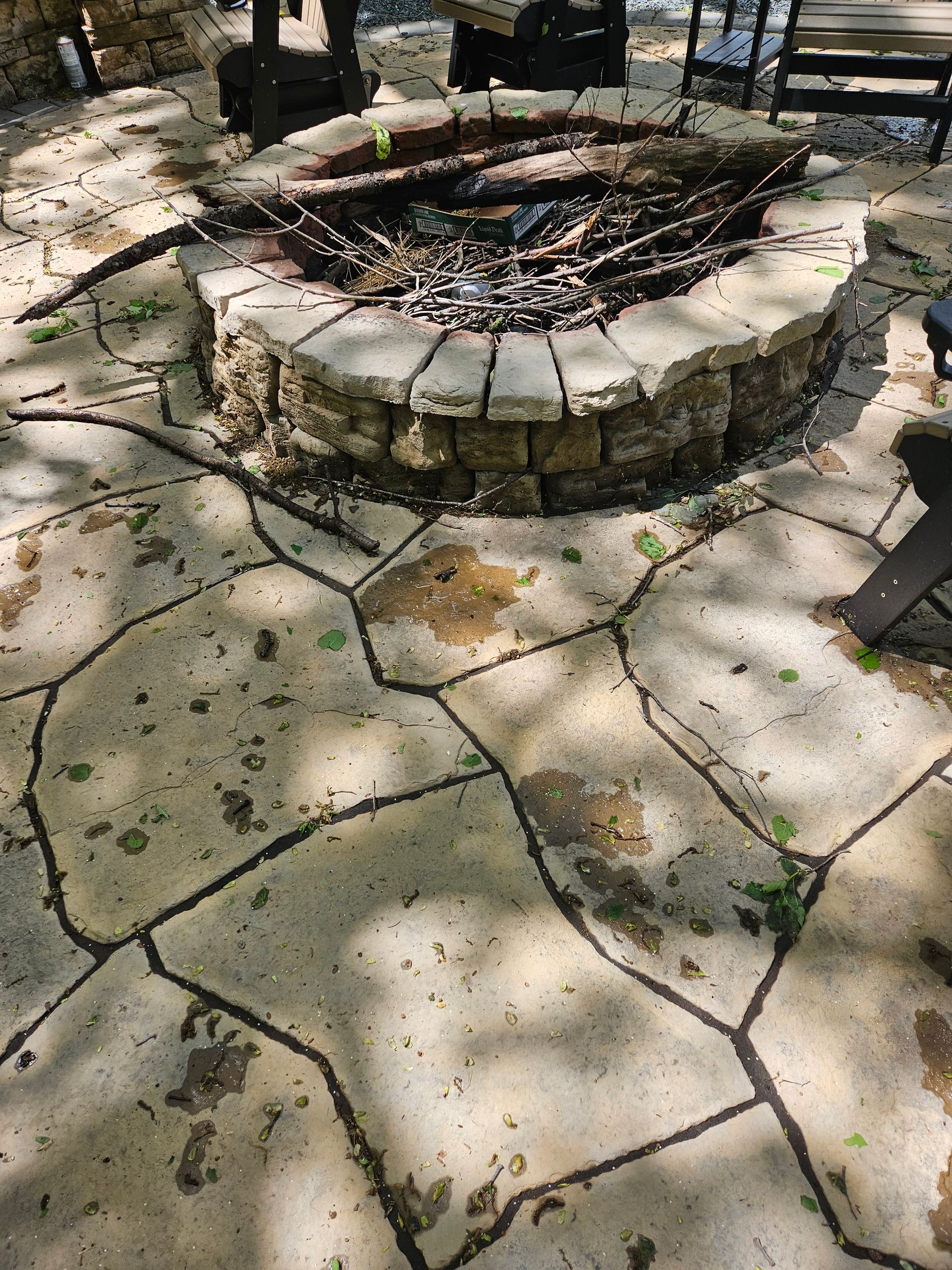 A stone fire pit surrounded by irregular flagstone pavers in a sunlit outdoor patio.