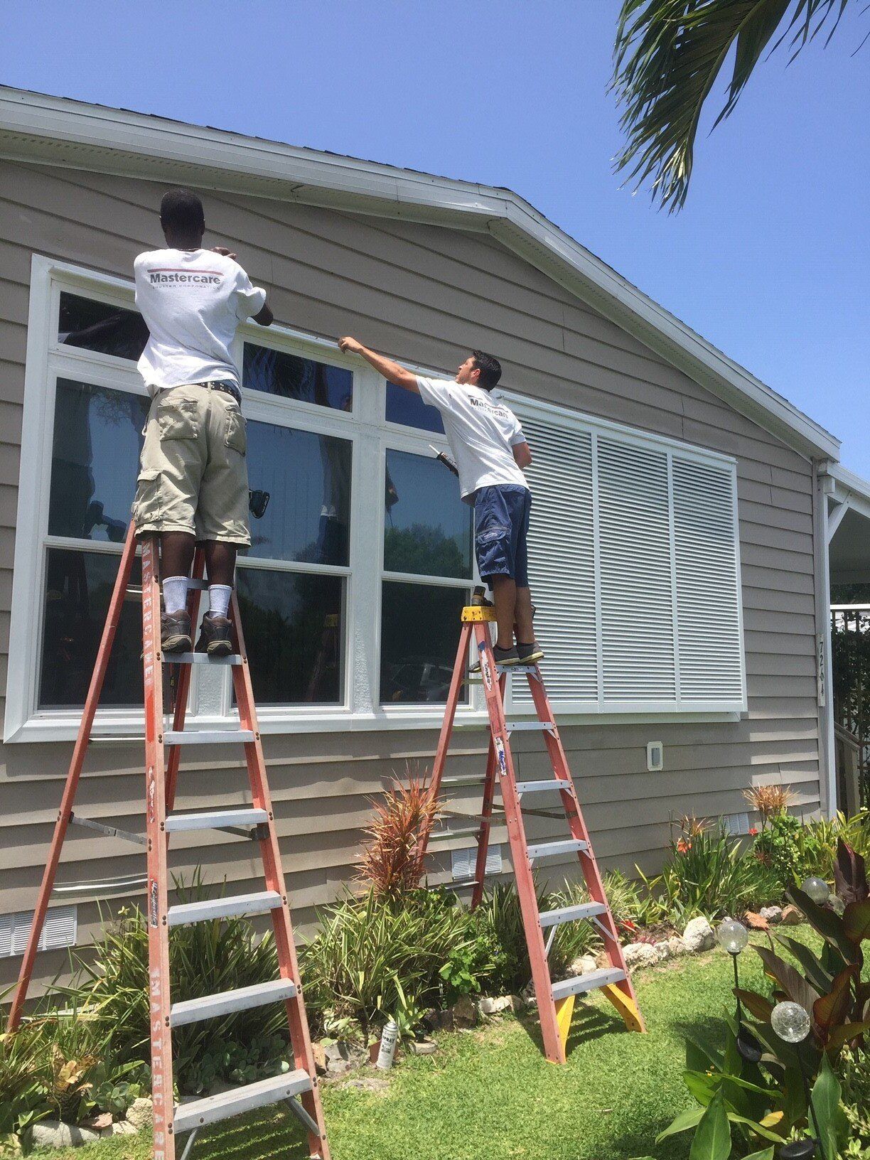 Two Men Installing Shutters — Hobe Sound, FL — Mastercare Shutter Corporation Two Men Installing Shutters — Hobe Sound, FL — Mastercare Shutter Corporation