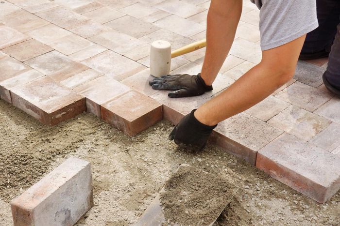 man installing walkway using stone