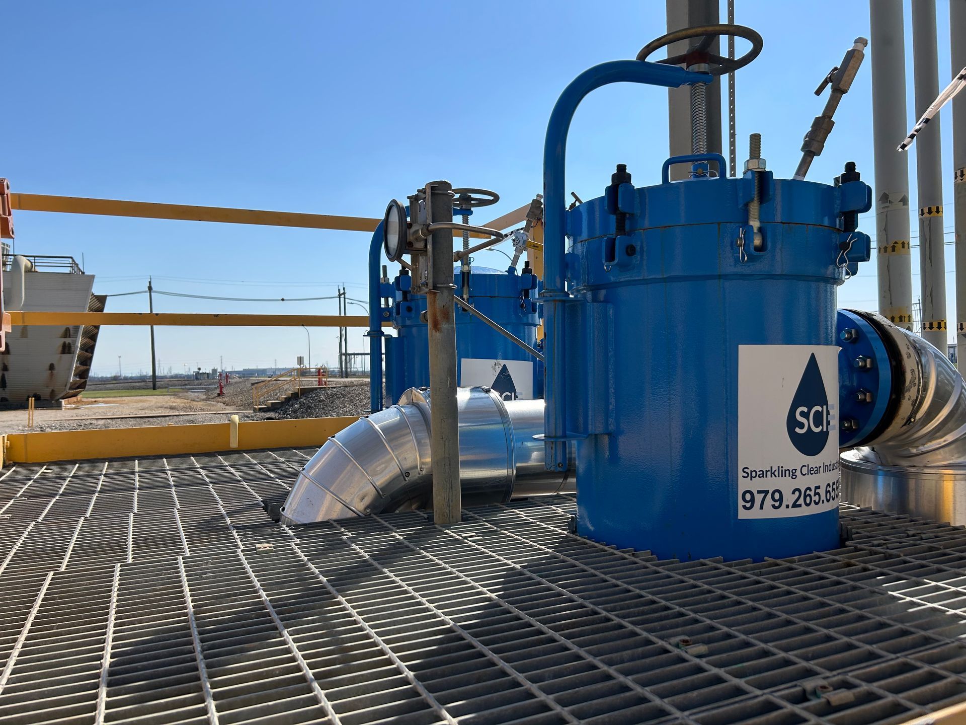 A blue filter housing from Sparkling Clear Industries with a white SCI logo on it is sitting on top of a metal grate.
