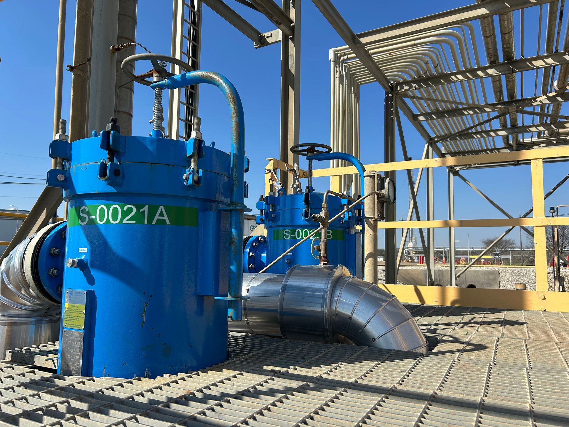 A few blue filter housing from Sparkling Clear Industries are sitting on top of a metal platform.