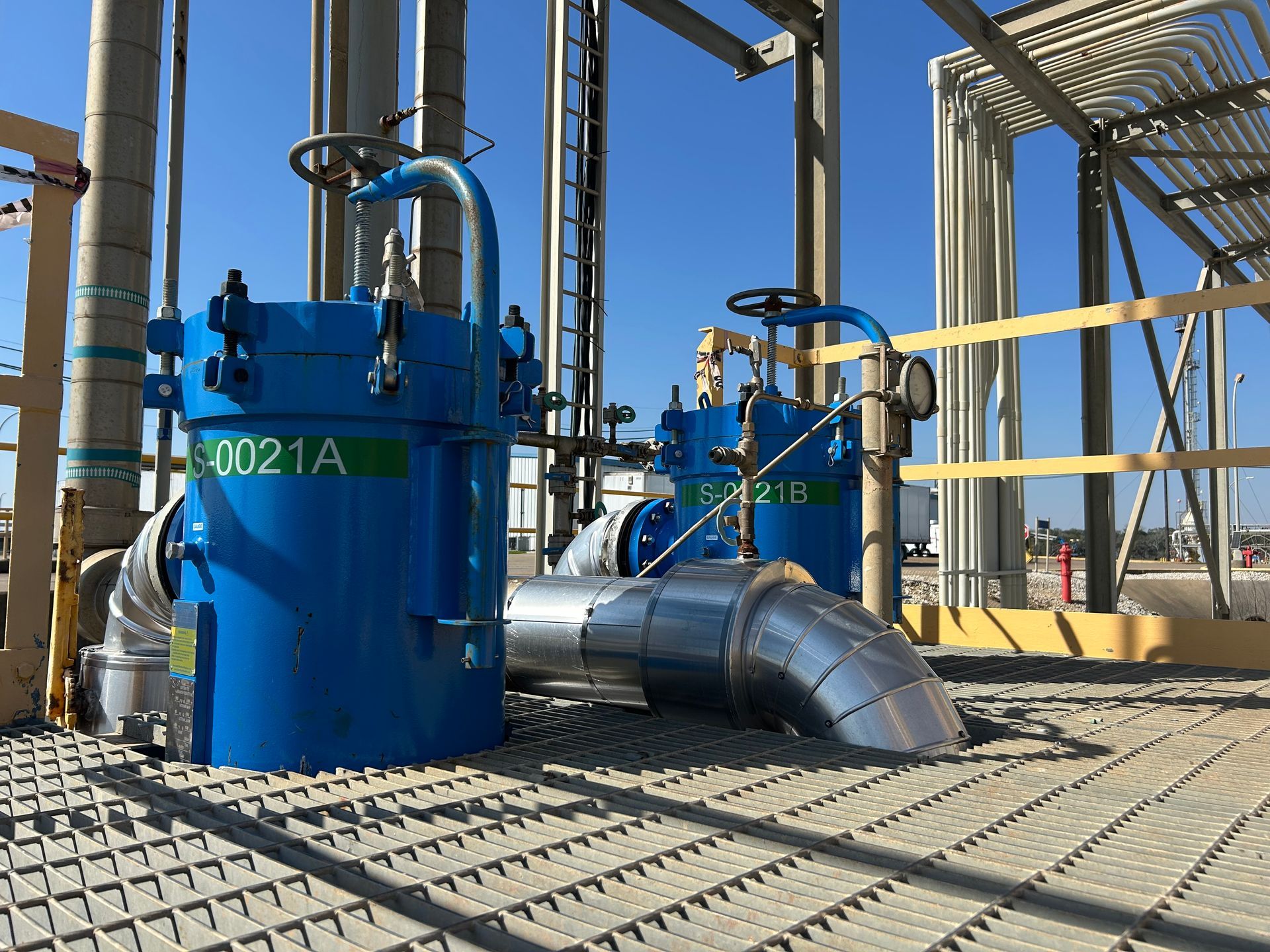 A bunch of blue filter housing from Sparkling Clear Industries are sitting on top of a metal platform.